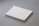 A stack of plain white paper sheets lies against a grey background. The edges of the papers are visible, and in the bottom corner of the top sheet, there is a small circular logo in blue ink.