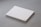 A stack of plain white paper sheets lies against a grey background. The edges of the papers are visible, and in the bottom corner of the top sheet, there is a small circular logo in blue ink.