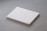 A stack of plain white paper sheets lies against a grey background. The edges of the papers are visible, and in the bottom corner of the top sheet, there is a small circular logo in blue ink.