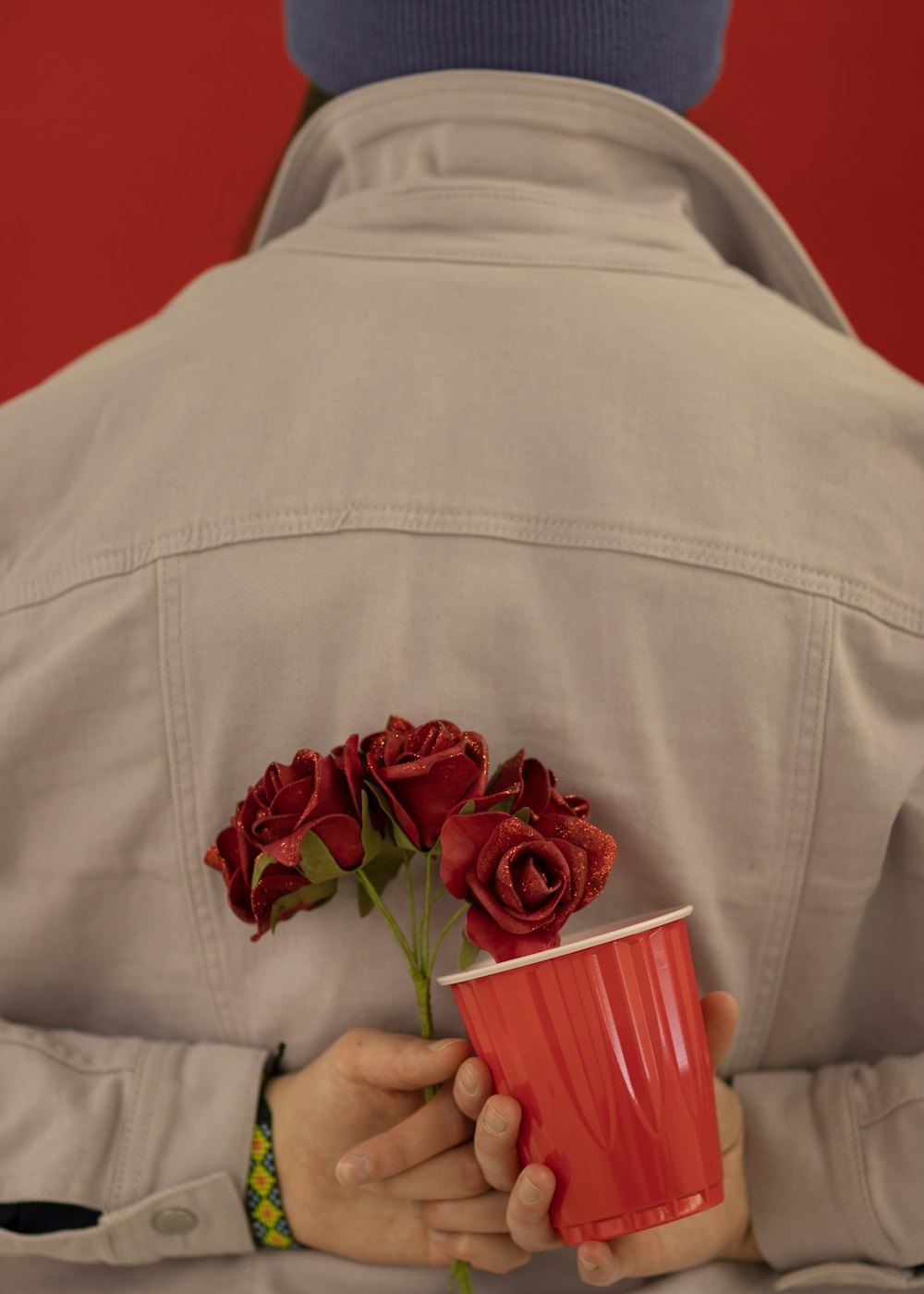 person holding red mug and red flowers