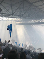 A panoramic view of the futuristic stadium filled with fans waving light blue and silver flags.