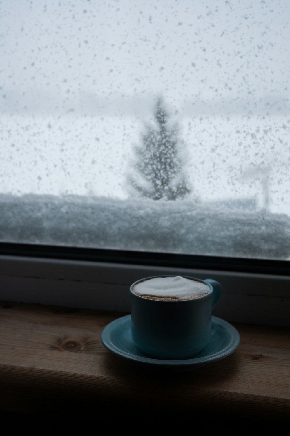 tazzina da caffè in ceramica bianca su piattino vicino alla finestra