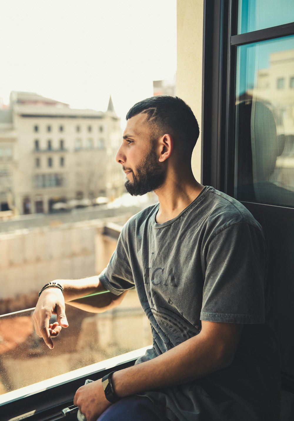 man in gray t-shirt by glass window