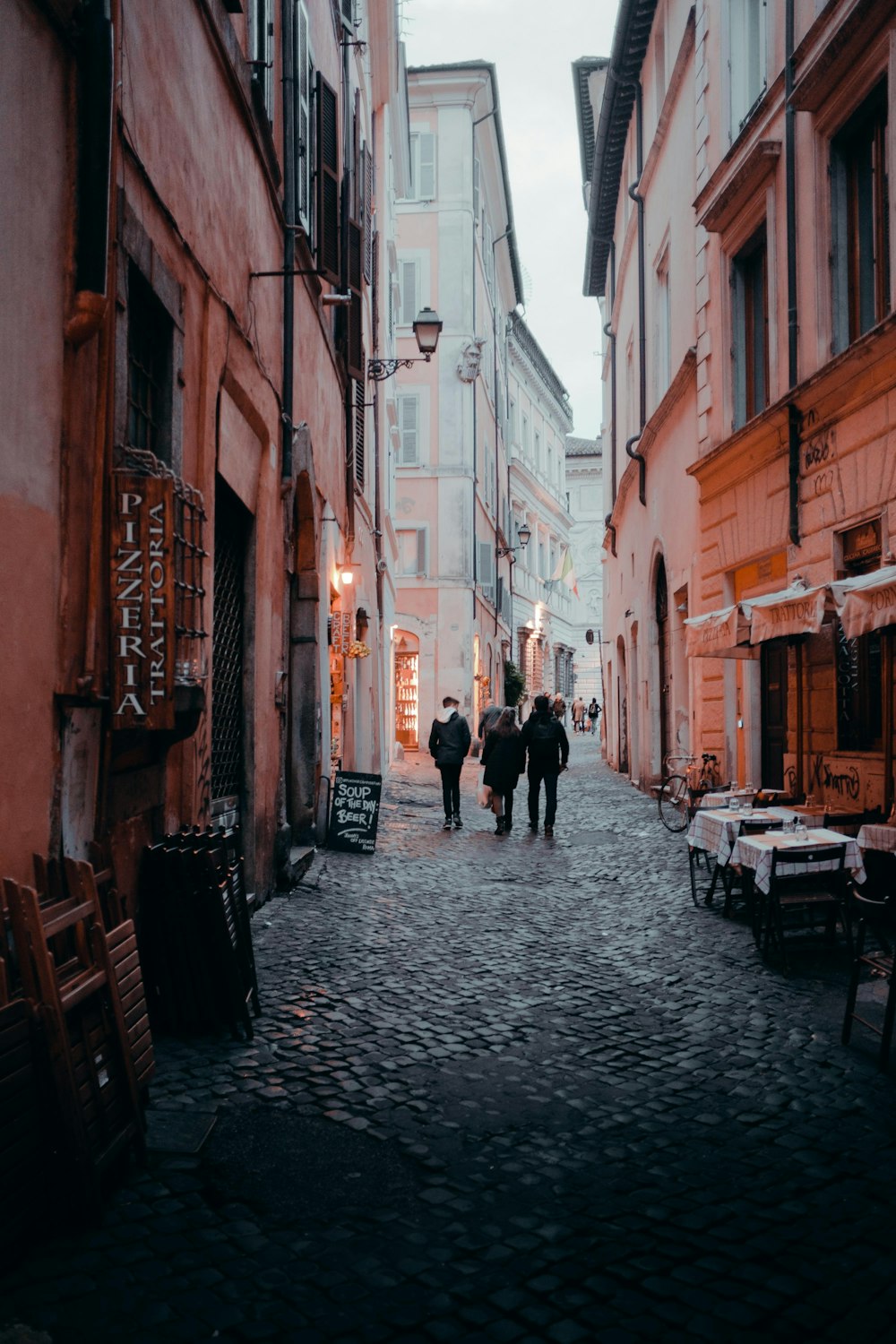 three persons walking between building during daytime