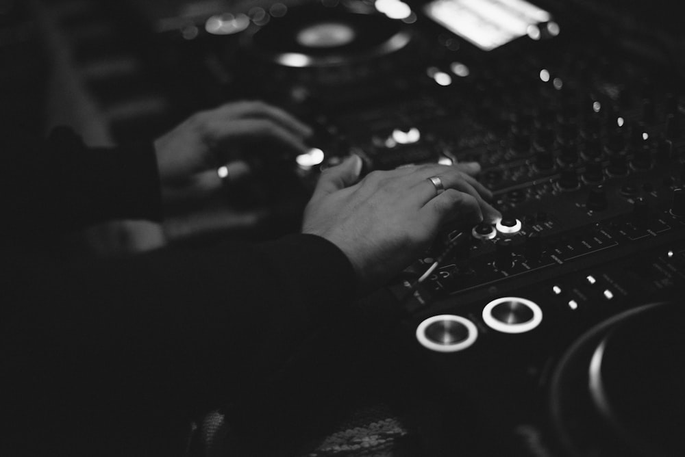 grayscale photography of person controlling a DJ mixer