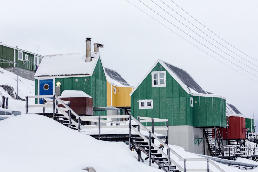 green wooden houses on snow covered slope under white skies