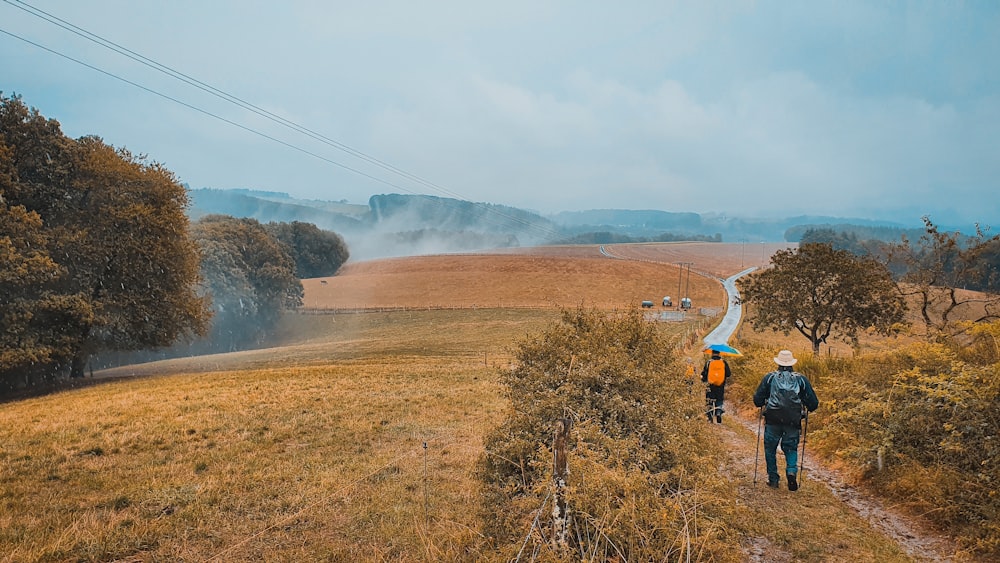 two hikers walks down the road at rural area