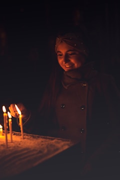 A smiling woman lighting a candle in support of World Kipa Day.