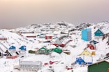 Colorful houses of a small Greenlandic village nestled against snowy hills.