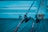Two fishing rods are positioned on a wooden surface, extending into the frame from the right. The background features softly focused steps, and the color palette includes shades of blue, giving the scene a calm, serene feel.