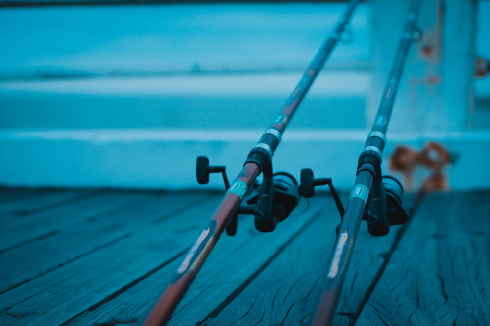 two black fishing rods on dock