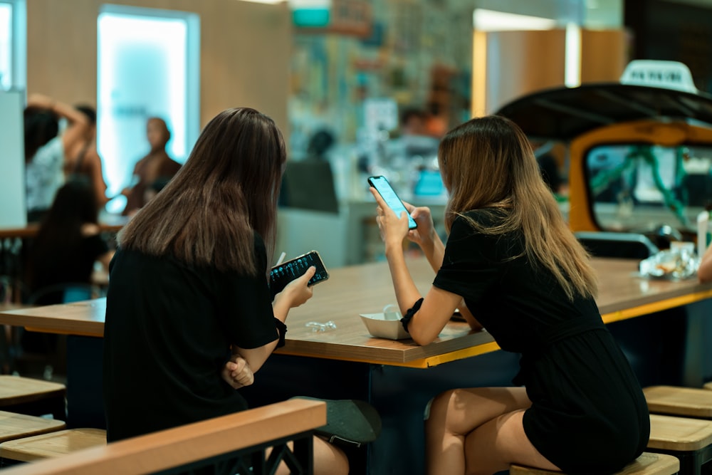 two women in black top sitting beside table