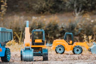 A collection of Tonka construction vehicles arranged in a sandbox.