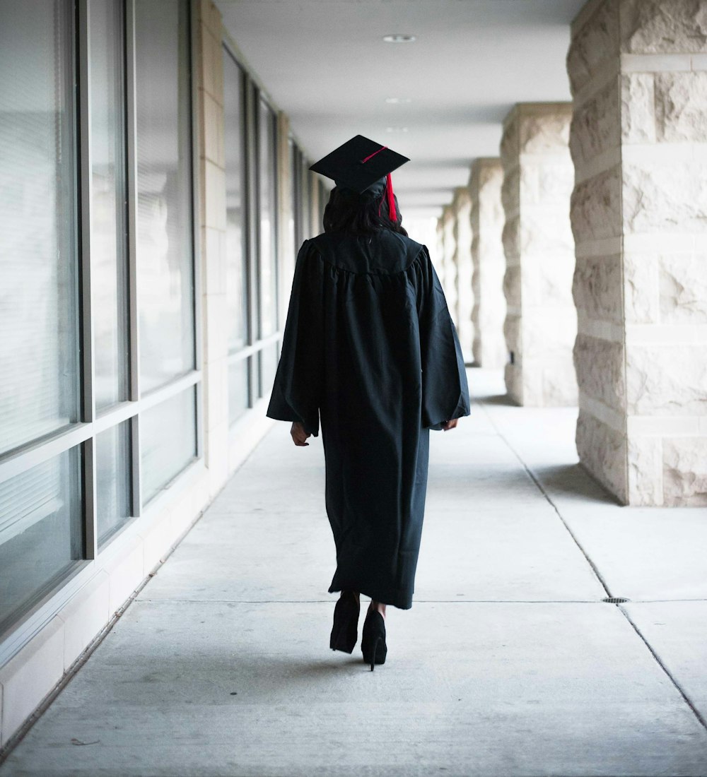 a person in a graduation gown walking down a hallway
