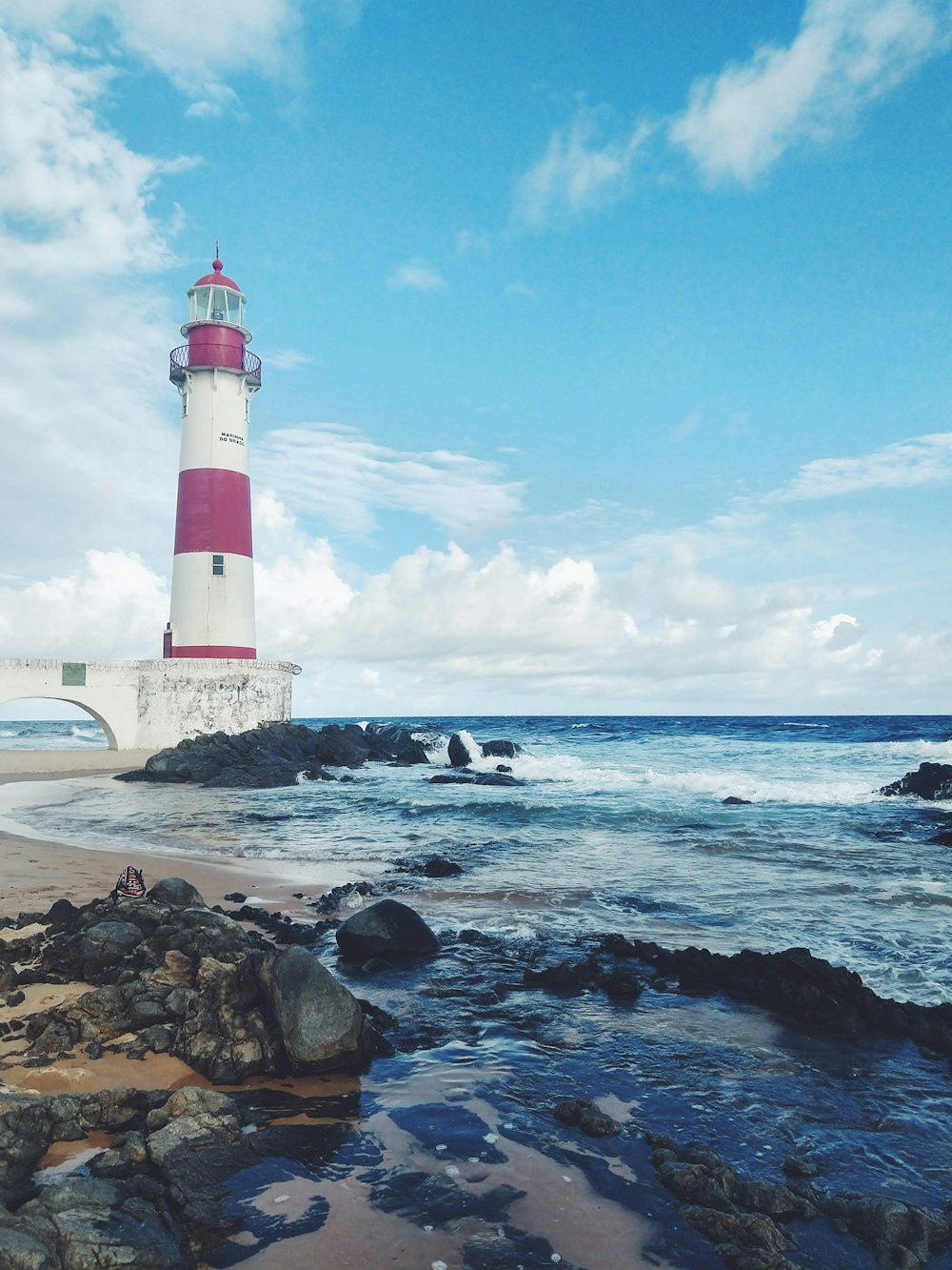 昼間の海辺の赤と白の灯台