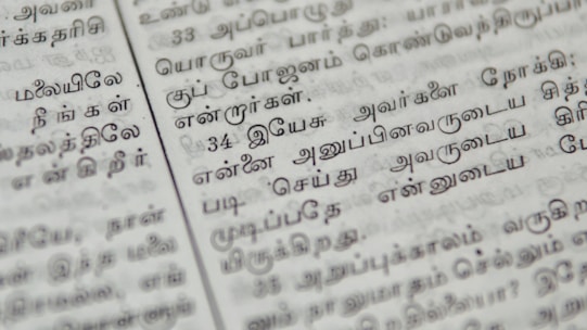 Close-up of handwritten Sinhala text on traditional paper with a pen.