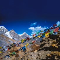 Colorful prayer flags fluttering against the backdrop of ancient monasteries perched on rocky hills.