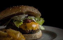 Close-up of a juicy cheeseburger with crispy fries on a rustic plate.
