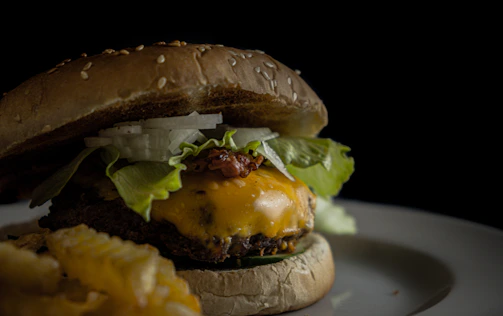 Overhead shot of a decadent burger with melted cheese and crispy fries on the side.