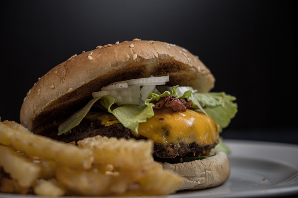 tasty burger with melted cheese and sesame seeds on top near potato fries