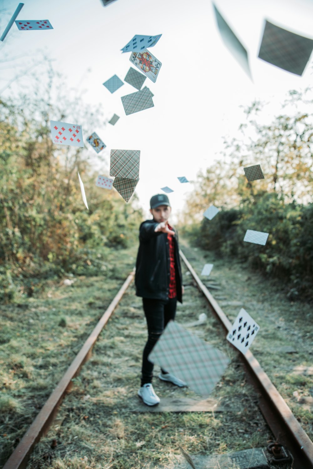 man in black jacket throwing playing cards