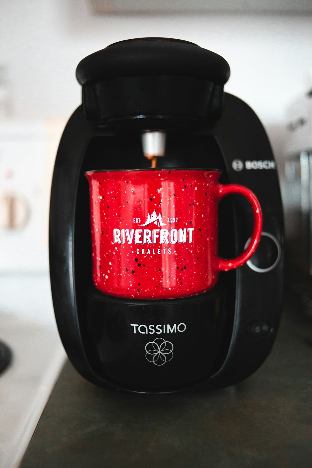 black Tassimo coffeemaker and red mug on black surface