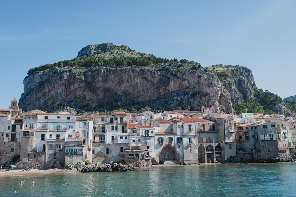 houses viewing mountain near body of water under blue and white sky