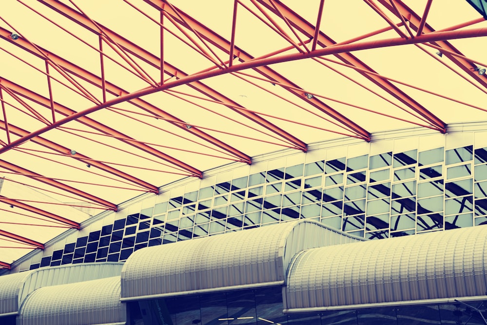 low-angle photography of red metal truss ceiling