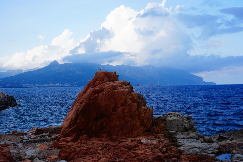 白と青の空の下で山を眺める青い海近くの茶色の岩層