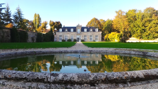 pond in front of building near trees during day in Rambouillet France