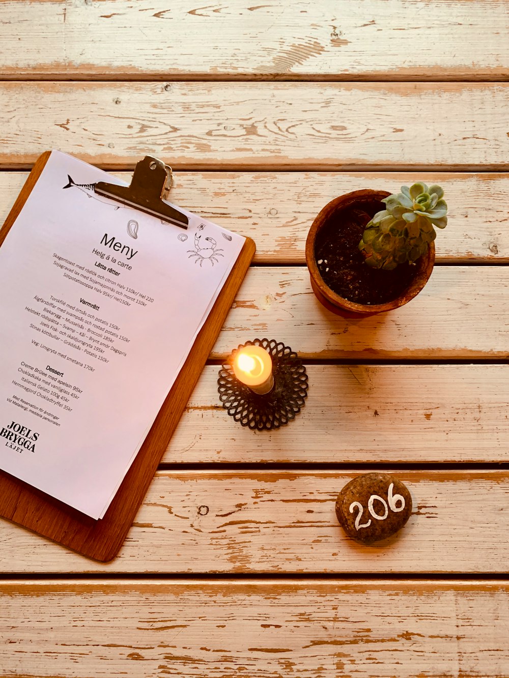 flat lay photography of a clipboard beside lighted candle and succulent
