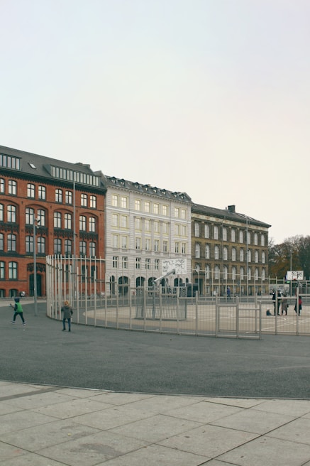 Children playing in the schoolyard surrounded by modern white and gray buildings with soft gradients.
