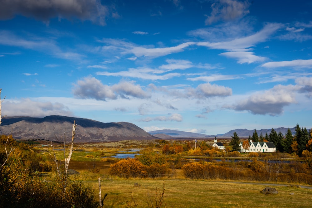 a scenic view of a mountain range with a house in the foreground