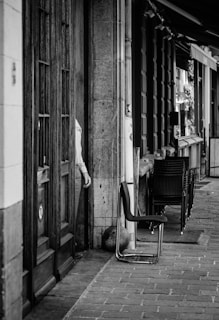 An empty chair by a window looking out onto a quiet street at dusk.
