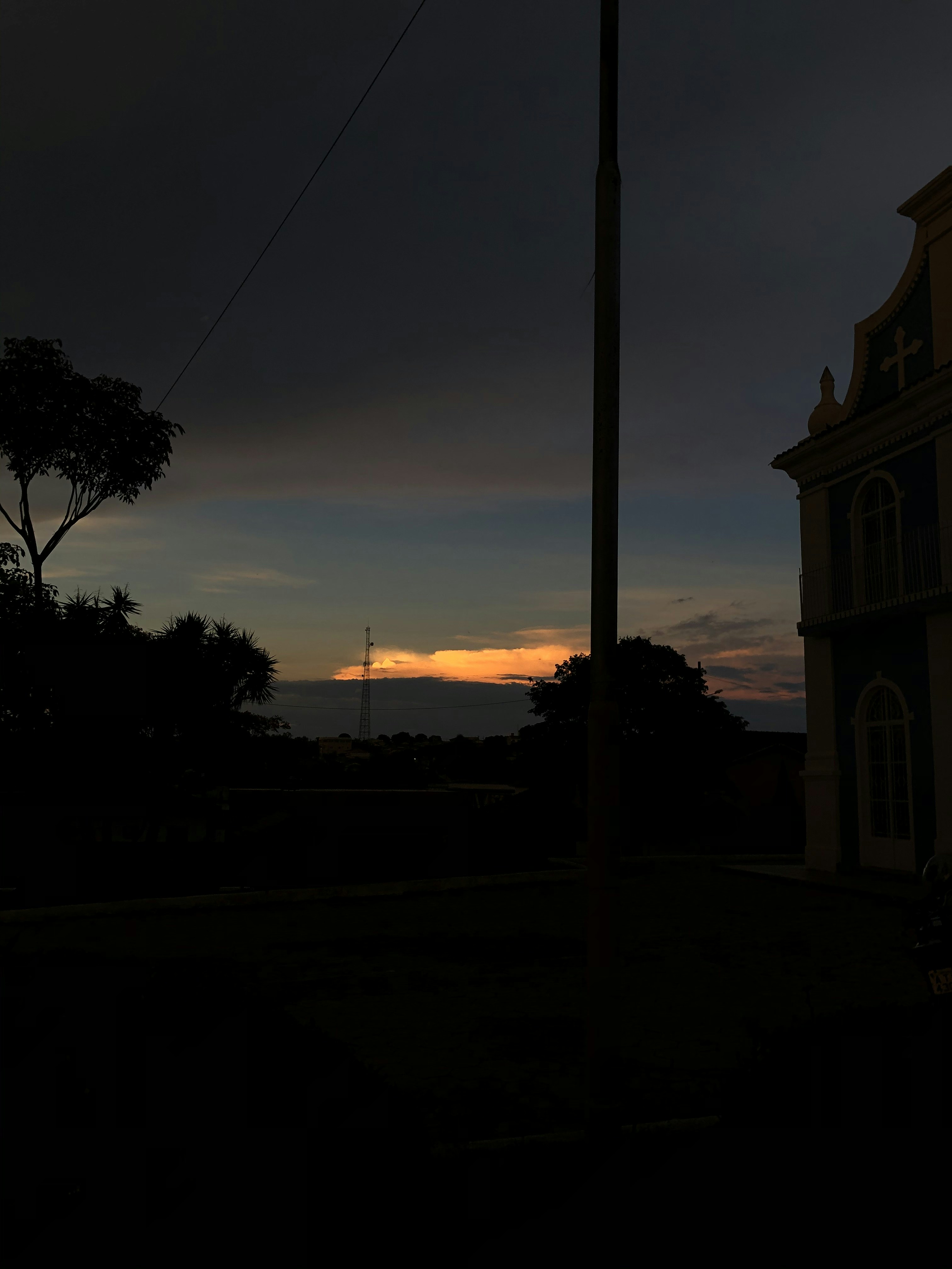 Dramatic cross silhouette against golden sunset sky, deep shadows and warm light rays, spiritual atmosphere