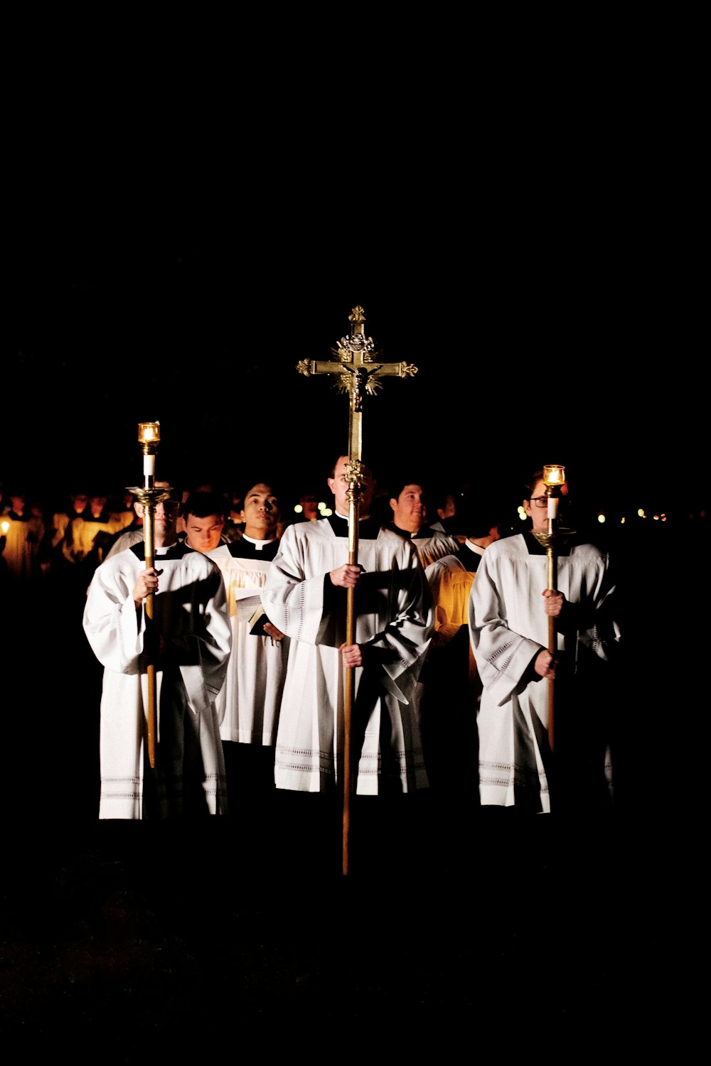 men holding cross and candle light