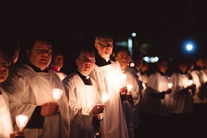 priests holding lighted candles at night