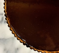 Close-up of a chocolate tart with glossy ganache topping.