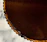 Close-up of a hand holding a beautifully decorated chocolate tart with a soft-focus background of a cozy kitchen.