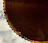 Close-up of a hand holding a beautifully decorated chocolate tart with a soft-focus background of a cozy kitchen.