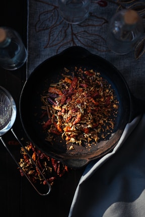 A cast iron pan resting on a wooden countertop beside fresh herbs.