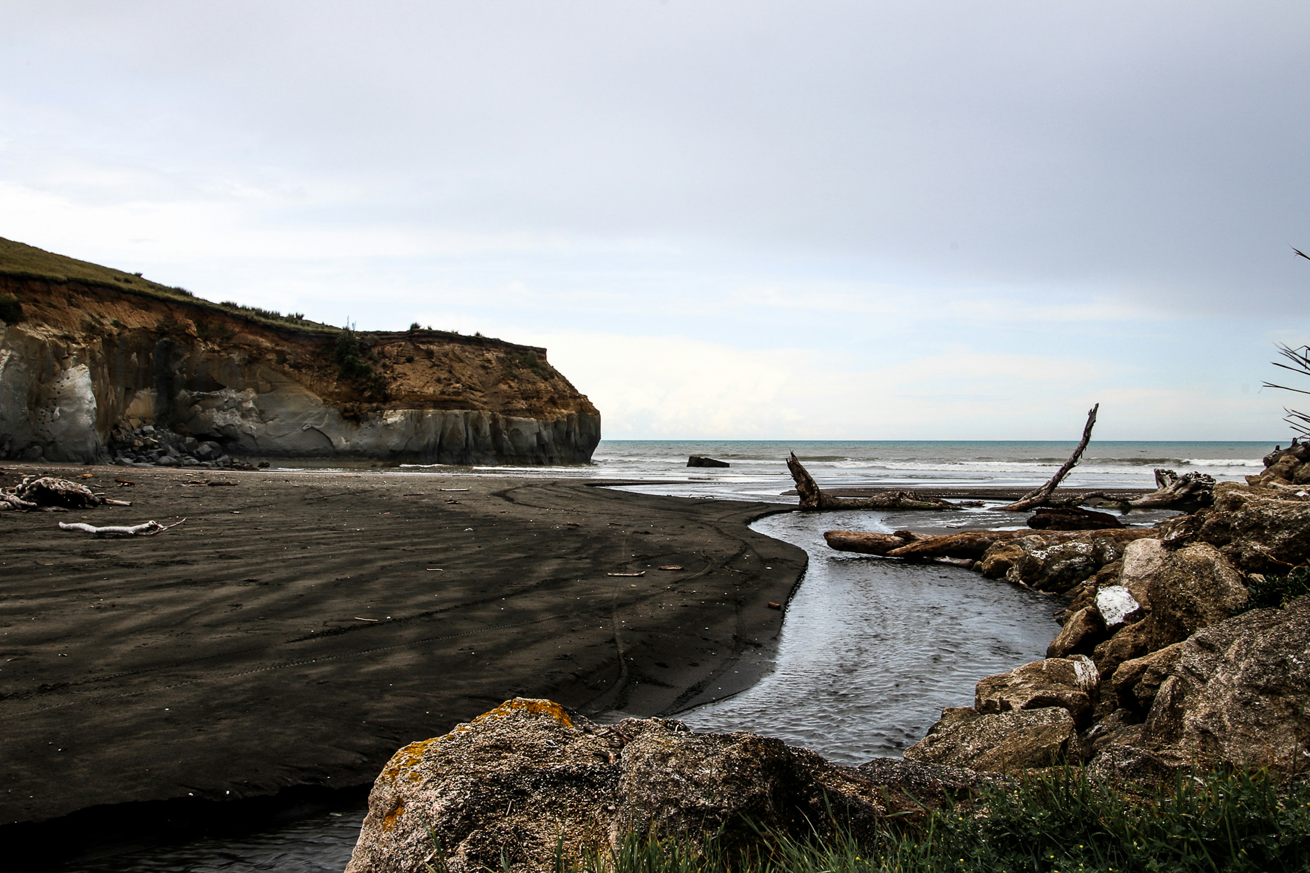 cliff facing ocean under white sky