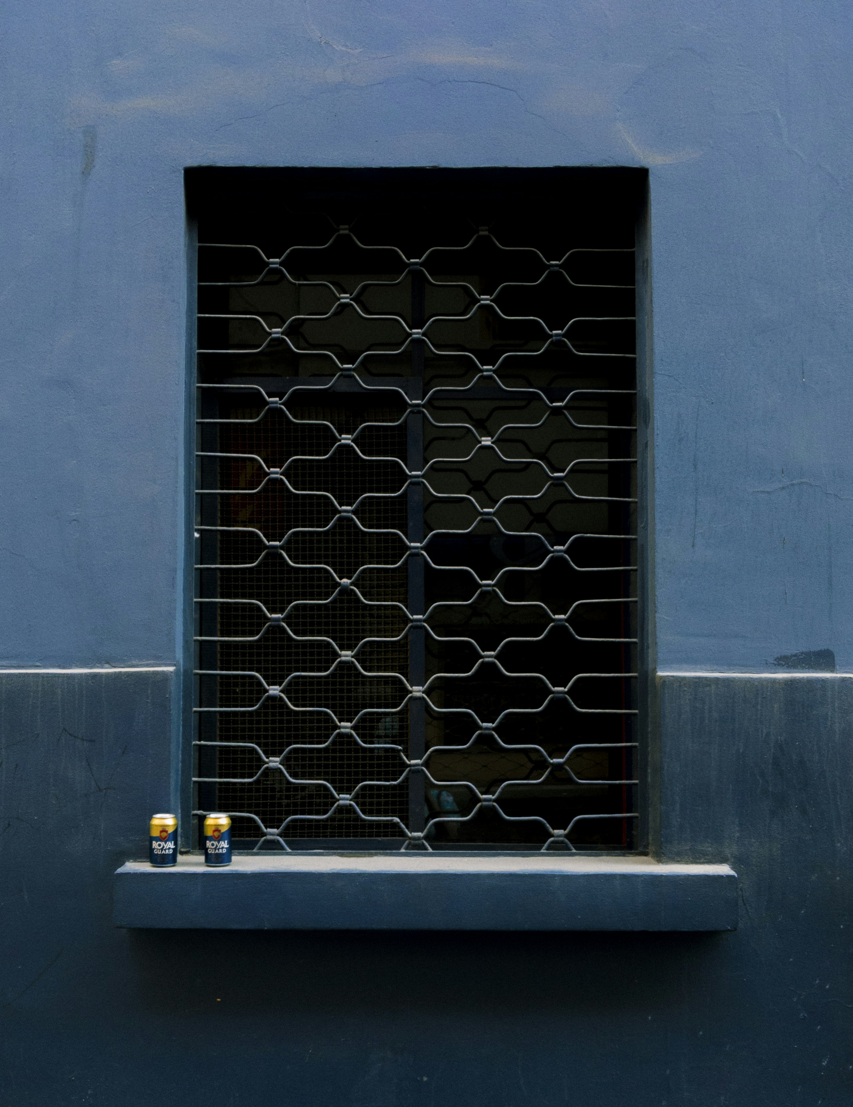 a blue building with a window and a cat sitting in the window sill