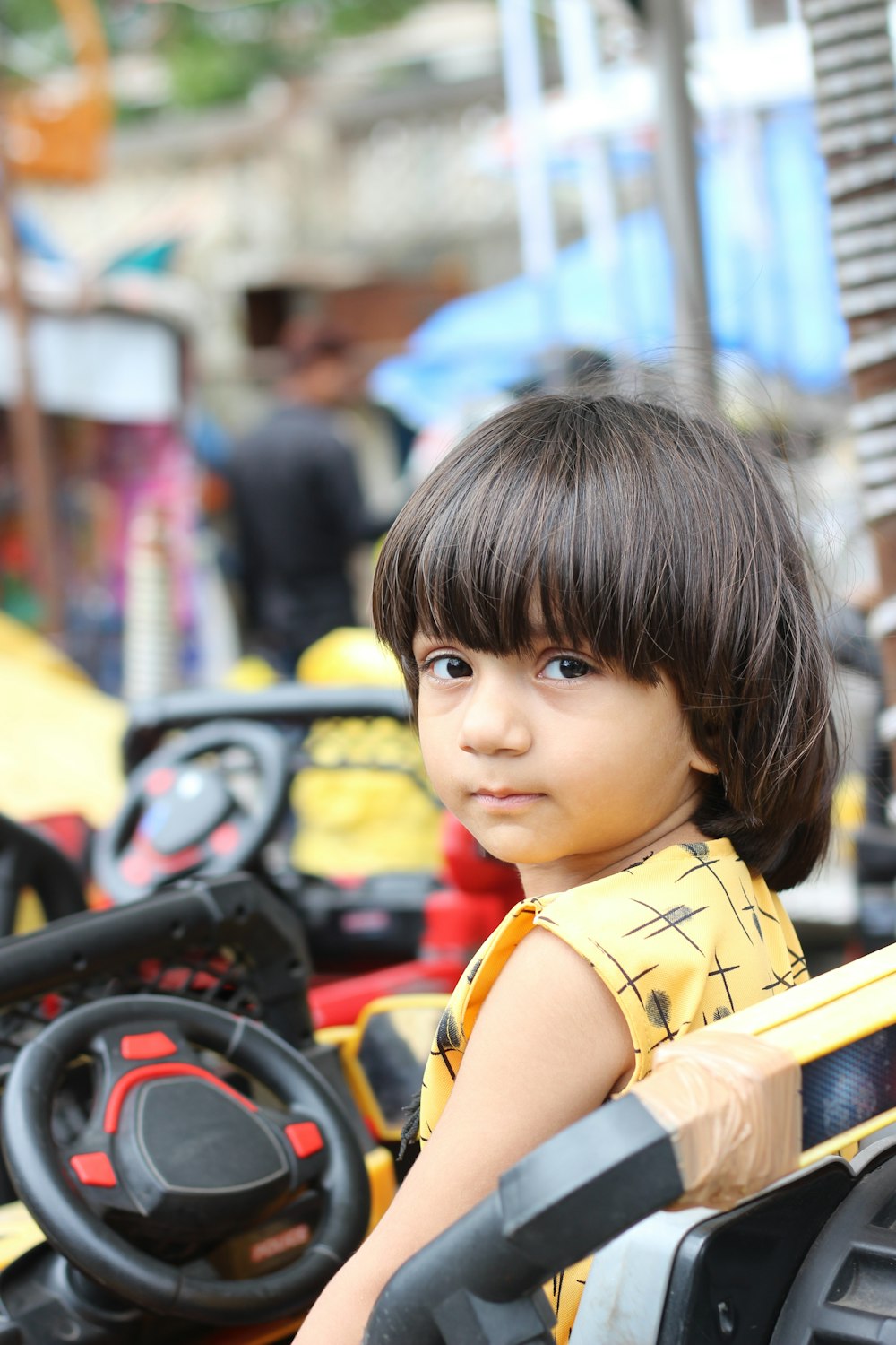 boy wearing yellow shirt riding ride on vehicle