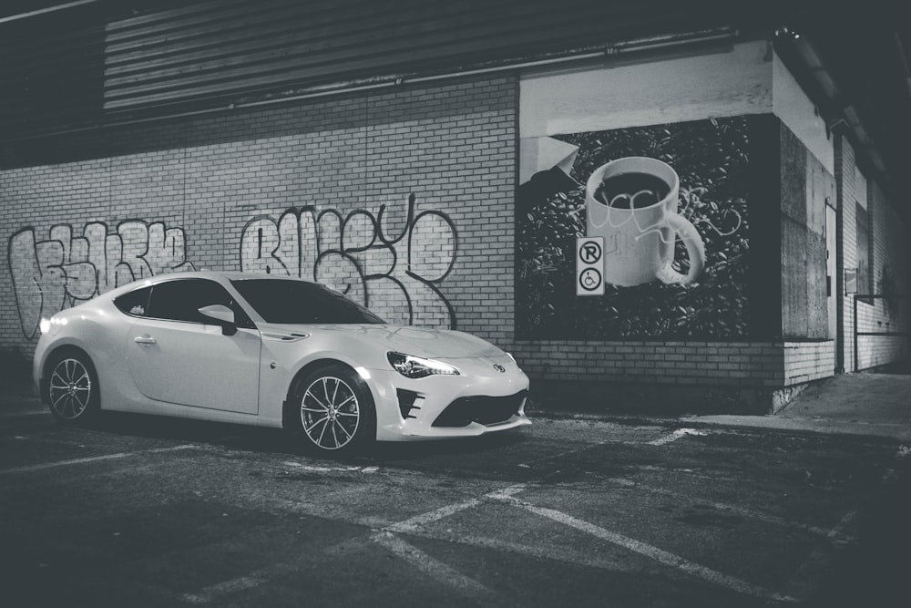 grayscale photography of a coupe parked on sidewalk