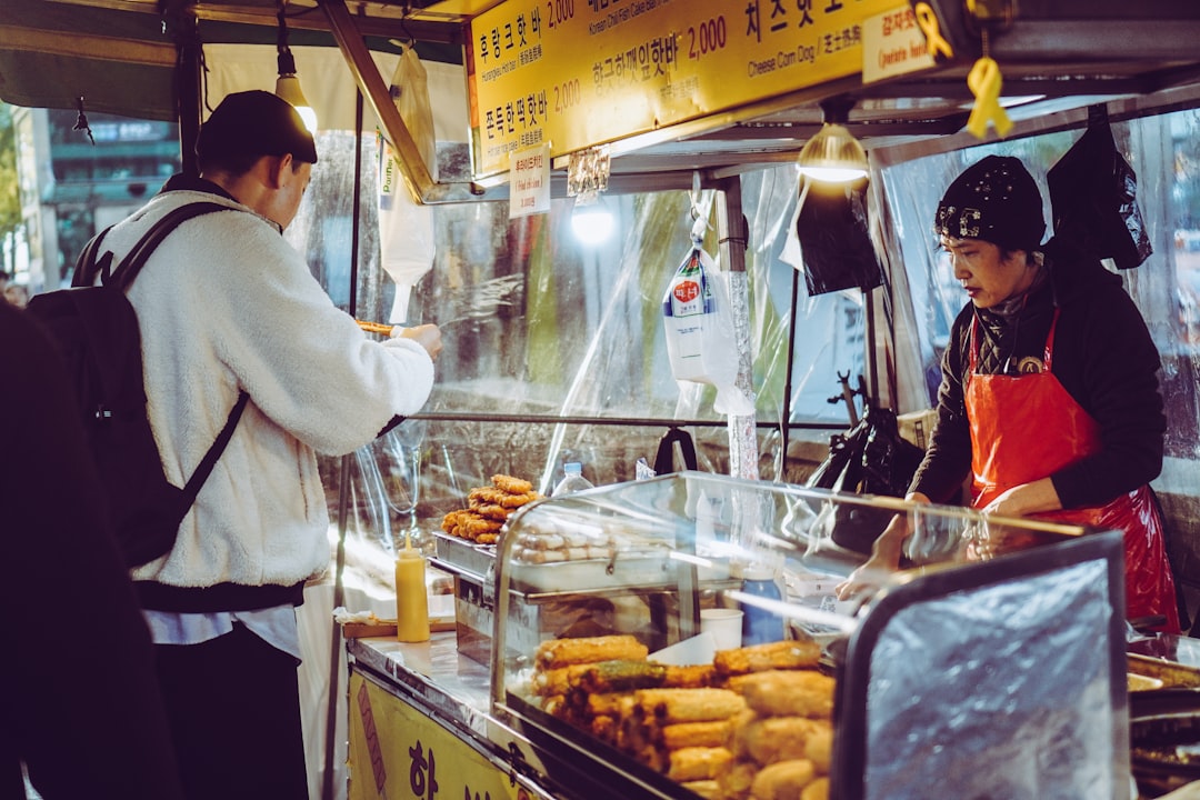 man eating food in front of food ventor at night