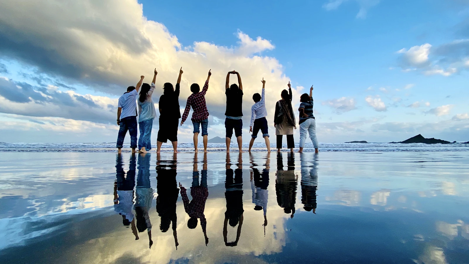 A community of people raising their hands together in joyful connection — reflecting the mission of The New Energy Collective