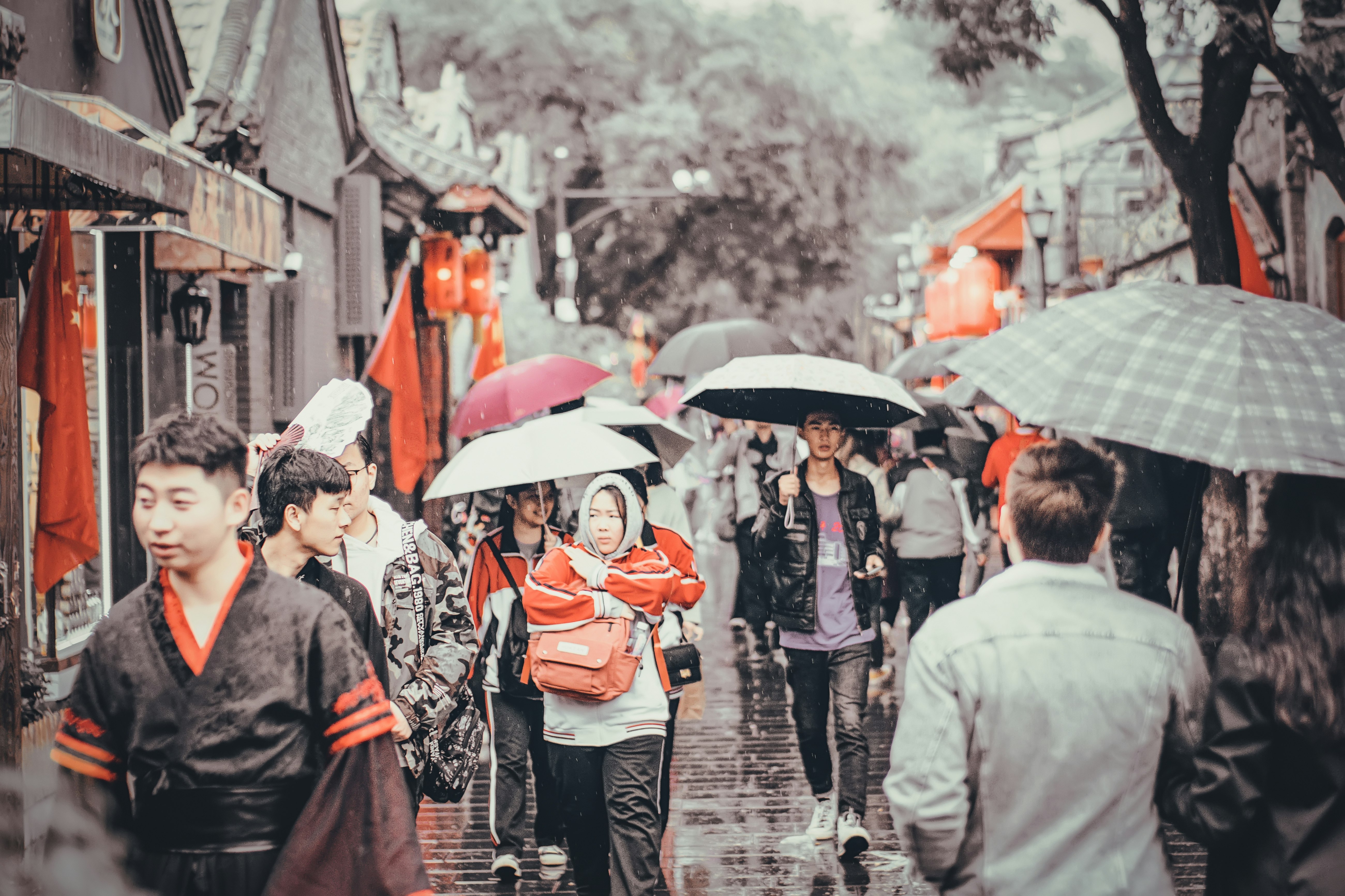 selective color photography of walking man and woman holding umbrellas