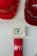 A set of red hard hats is mounted on a wall above an emergency alarm system. The alarm consists of a button to break glass in case of emergency and a red panel beneath it.