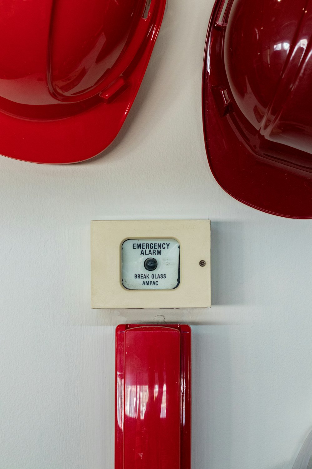dois capacetes vermelhos perto do botão de alarme de emergência
